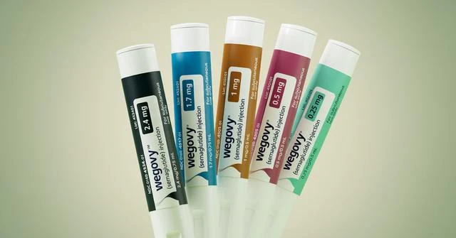 Five injector pens arranged in a fan against a pale green background.